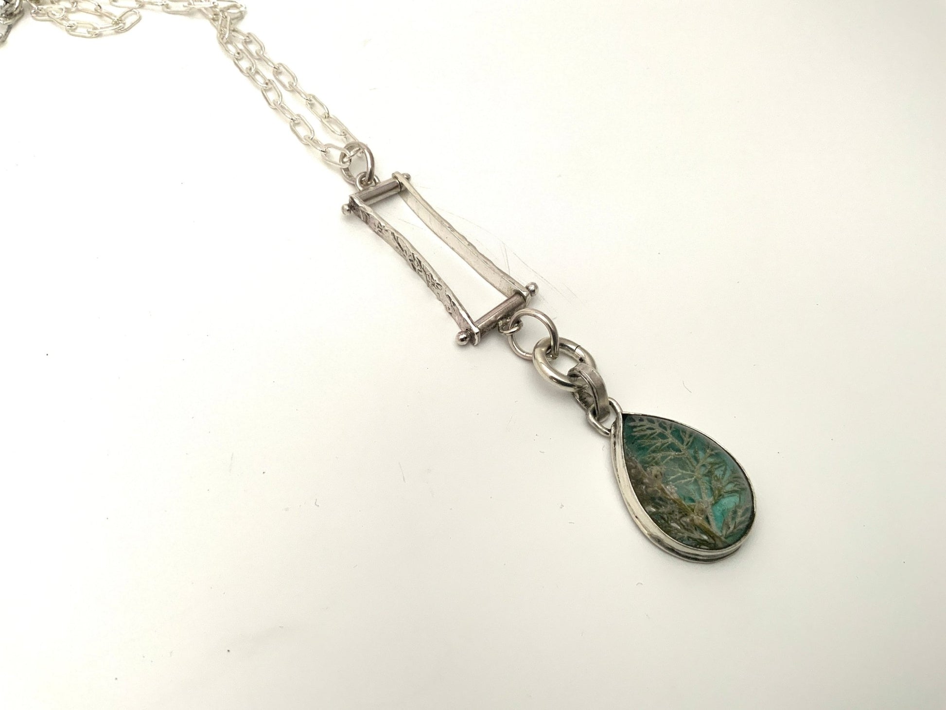Botanical pendant with yarrow and tiny flowers preserved in resin over watercolor background